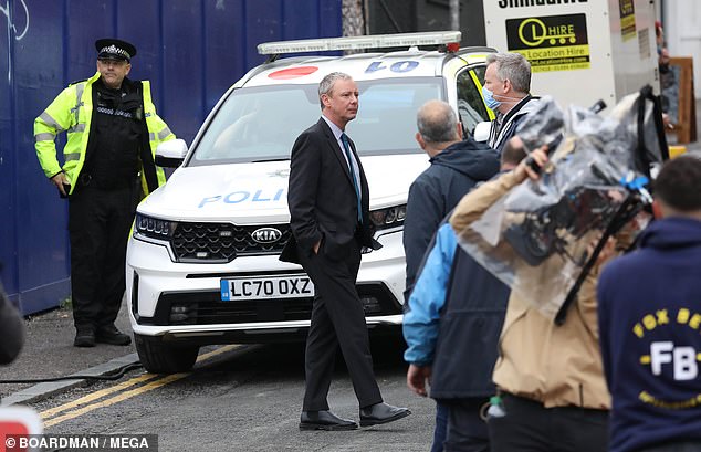 Putting on an act: John stood near a police car on a piece of wasteland in the south coast city of Brighton which was made to look like a crime scene. Photo: Boardman/Mega